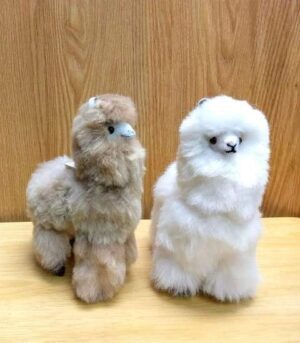 Plush alpaca toys on wooden surface