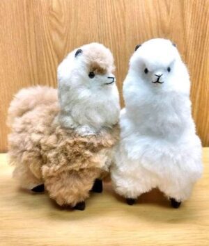 Cute stuffed alpacas on wooden surface