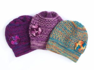 Three vibrant knit beanies with flowers