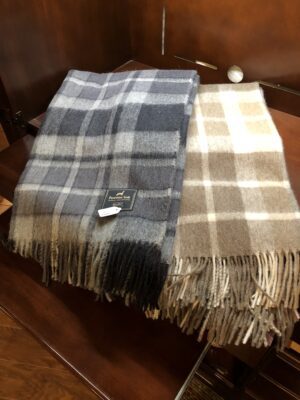 Two cozy plaid scarves, one gray and one beige, laid on a wooden surface.