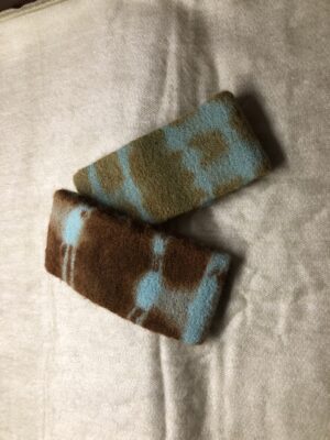Two knitted wrist warmers with colorful patterns on a fabric surface.