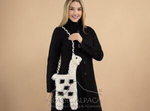 Woman in black holding a white, spotted alpaca-shaped bag.