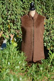 Brown sleeveless vest displayed outdoors among greenery.