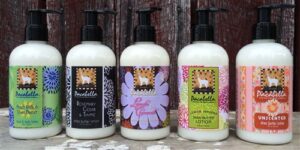 Three bottles of hand lotion with animal-themed labels on a wooden background.