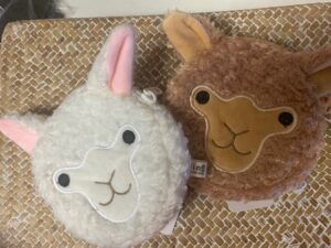 Two plush alpaca toys with cute faces, one white and one brown.
