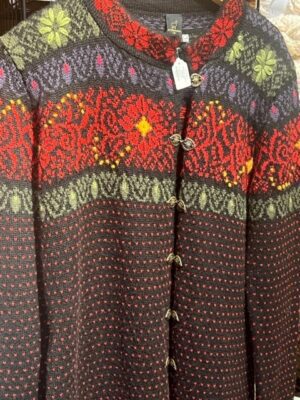 Close-up of a patterned button-up sweater with red, green, and brown colors.