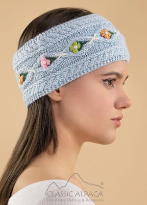 Woman wearing a light blue knitted headband with small colorful flowers.