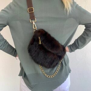 Person wearing a green jacket with a black fur crossbody bag.