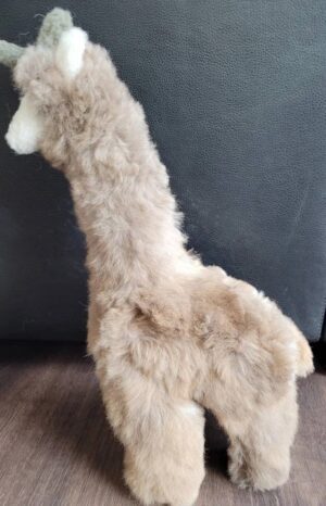 Fluffy beige llama plush toy on a dark surface.