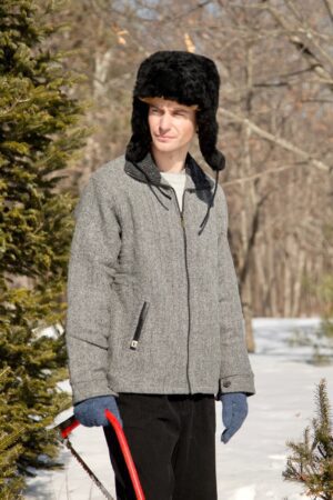 Man wearing a gray coat and black fur hat outdoors.
